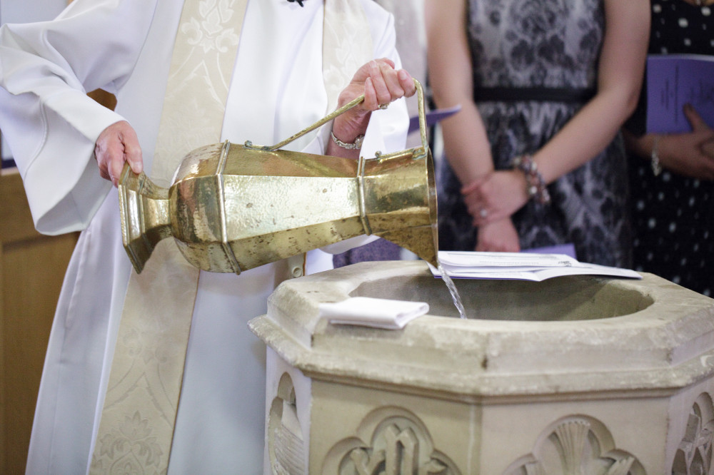 Water being poured in to a font with a large gold coloured jug