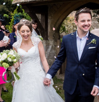 A bride and groom having confetti thrown over them outside church